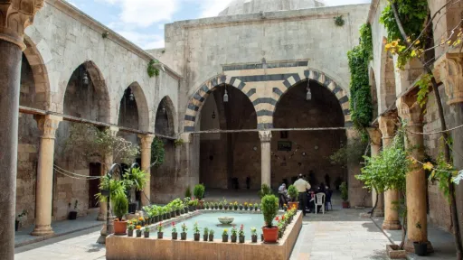 Maristan Argun von Aleppo, ein arabisches Gebäude mit Bogengängen und einem Wasserbecken in der Mitte eines bepflanzten Innenhofs